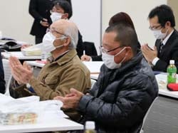 拍手で議案を採択する出席者