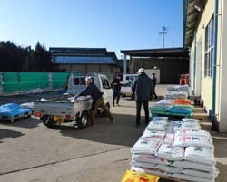 農家のトラックに肥料を積み込む職員