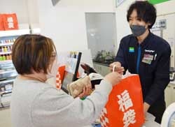 福袋を購入し斉藤店長から受け取る来店者