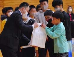 網野部長から牛乳などを受け取る児童