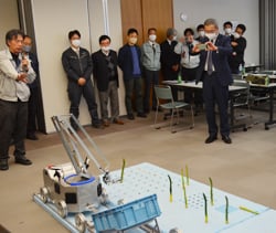 自動収穫機のデモを見学する出席者