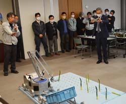 自動収穫機のデモを見学する出席者