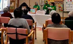 利用者へ読み聞かせを行うにこにこの会のメンバー
