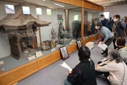乙事区役所内の歴史ある仏像等をじっと見つめる部員
