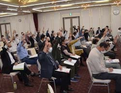 議案に対し挙手で賛成する出席者（長野県伊那市で）