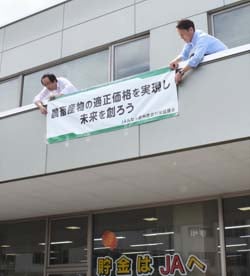 スローガンを掲げた横断幕を設置するJA職員