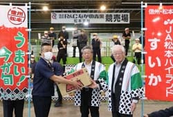 西澤智成支社長（左）にすいかを手渡す田中組合長（中）と三村晴夫常務理事（右）