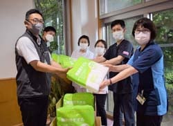 パルで購入したタオルを手渡す実行委員（左）
