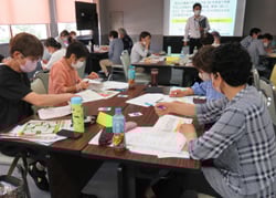 ゲームで意見を出し合う部員とアドバイスをする講師