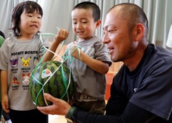 園児にスイカを手渡す粟津原後継営農部長（右）