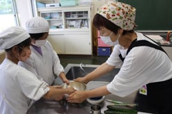 女性部員のサポートでピザづくりを楽しむ児童ら