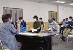 毒きのこについて説明する丸山さん（手前）と確認する出席者