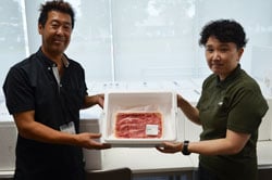 牛肉を受け取る矢崎さん（右）と手渡すJA職員