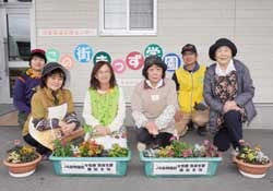 学園の正面玄関前で花の受け渡しを終えた牛山園長（前列左から2人目）と参加者