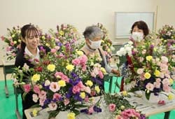 子どもたちに贈るフラワーアレンジメントをつくる女性部員と役職員