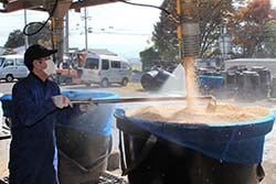 破砕もみに乳酸菌入りの水を加えるSGSの製造作業