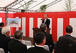 起工式で挨拶を述べる千國茂組合長（中央）と建物のイメージパネル（左）