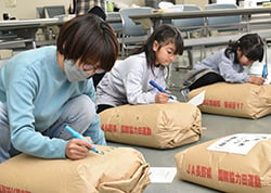米袋にメッセージなどを書き込む参加者ら