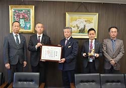 賞状を手渡す稲垣業務係長（左から2人目）と受け取る西村組合長（中央）