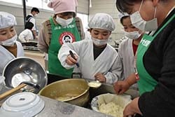 固まった豆腐をおたまで移す女性部員（右）