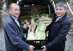 上原さん（左）に活動協力への感謝を伝え、野菜を受け取る小口所長
