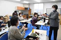 飾りの作り方を教わる女性部員