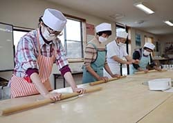 そば生地を丁寧に伸ばす参加者