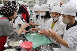 JA女性部メンバーに教わり五平餅を作る児童ら
