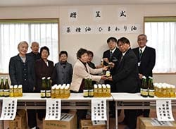油を寄贈する細萱代表（左から5人目）とセンター長ら