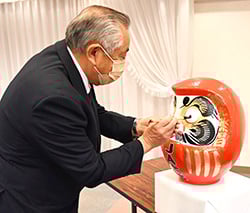 式でだるまに目を入れる武井組合長