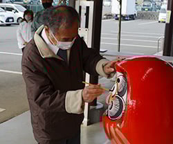 豊作を願ってだるまに目を入れる出羽沢会長