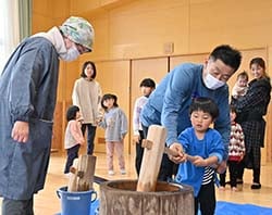餅をつく参加者とJA職員（中央）