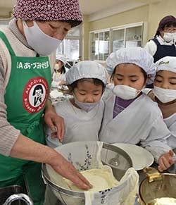 完成した豆腐に興味津々な児童と北林委員長（左）