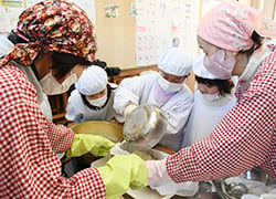 鍋から豆腐の型枠に液を移す児童をサポート