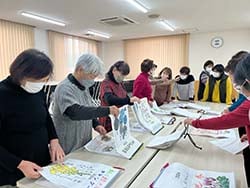 完成した絵手紙カレンダーを見せ合う受講生