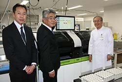 矢澤統括院長（右）に医療機器を受け渡す小平組合長（中）ら