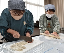 そばを細かく切る部員（左）と生地を伸ばす部員（右）