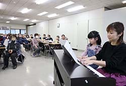 定期総会報告会の催しで後藤さん親子がピアノ演奏を披露し、聴き入る会員