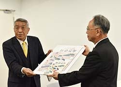 企業・団体の代表として冊子（パネル版）を贈る二村常務（左）と橋本教育長（右）