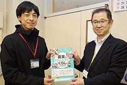 山﨑教諭（左）に「農業と私たちのくらし」を手渡す浜統括所長