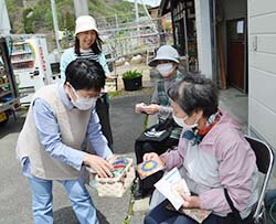 たわしを手渡す会員（左）と受け取る利用者