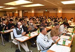 拍手で議案を承認する会場（長野県長野市、5月7日）