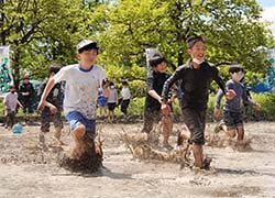 元気いっぱいに代かきを楽しむ長地小学校の児童