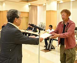 委嘱状を受け取る本木倫吉さん（右）