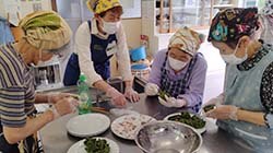 生地にあんこを包んで草餅を作る参加者