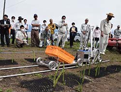 改良された自動収穫機を確認する参加者
