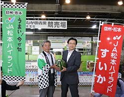 倉﨑浩社長（右）にすいかを手渡す田中組合長（左）