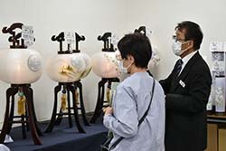 盆提灯の特徴を説明する担当者と来場者（左）