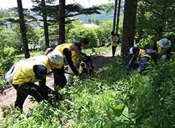 額に汗を流しながら植栽を行うJA職員