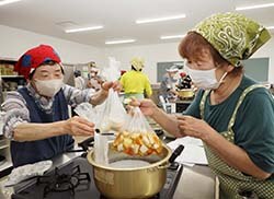 ポリ袋に入れた食材を鍋に入れる部員